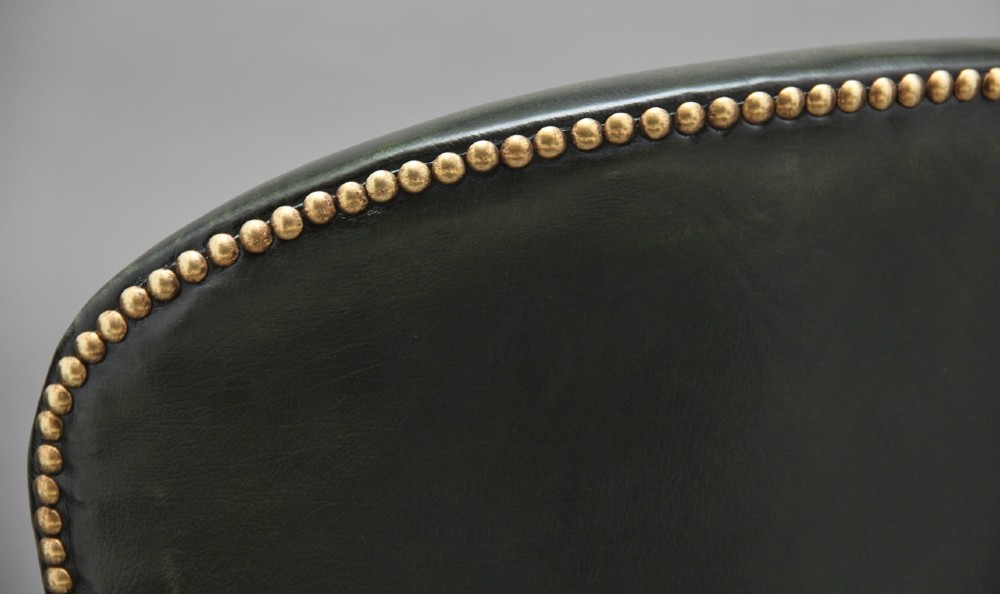 A 19th-century mahogany open armchair upholstered in dark green leather with brass studding and fluted front legs. View XII