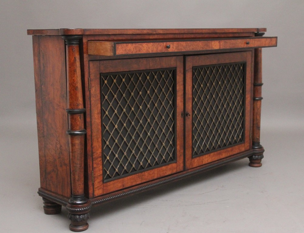 An early 19th-century Regency pollard oak side cabinet featuring two brass lattice grille doors, ebony stringing, and turned flanking columns. View IV