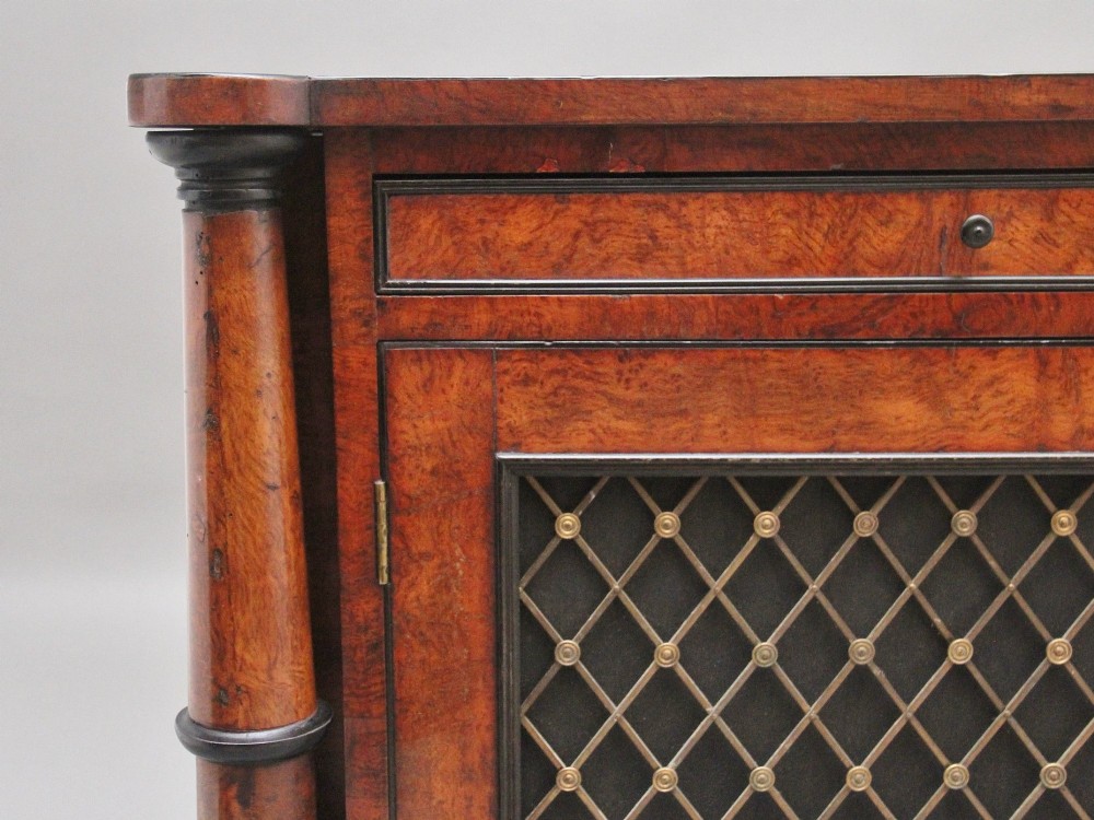 An early 19th-century Regency pollard oak side cabinet featuring two brass lattice grille doors, ebony stringing, and turned flanking columns. View X