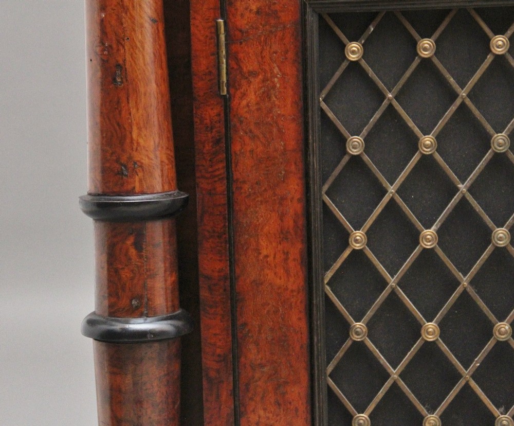 An early 19th-century Regency pollard oak side cabinet featuring two brass lattice grille doors, ebony stringing, and turned flanking columns. View XI