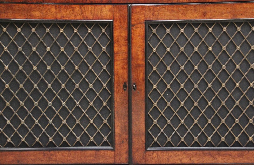 An early 19th-century Regency pollard oak side cabinet featuring two brass lattice grille doors, ebony stringing, and turned flanking columns. View XIV