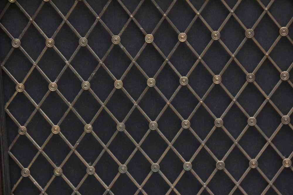 An early 19th-century Regency pollard oak side cabinet featuring two brass lattice grille doors, ebony stringing, and turned flanking columns. View XV