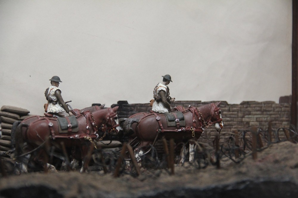 A glazed wooden display case containing an early 20th-century military diorama of a horse-drawn artillery team on a WWI battlefield scene. View V