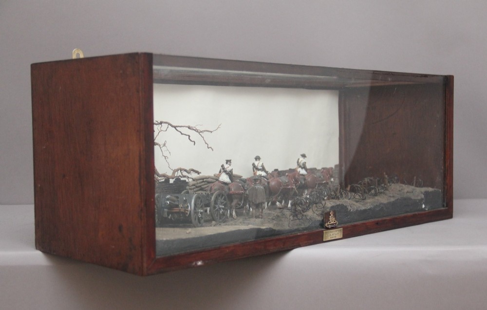 A glazed wooden display case containing an early 20th-century military diorama of a horse-drawn artillery team on a WWI battlefield scene. View VII