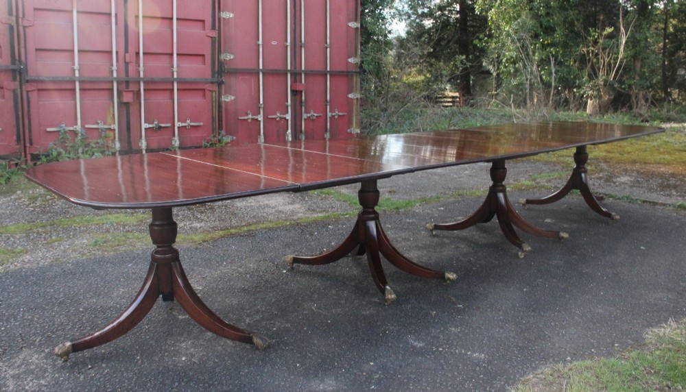 An exceptionally long early twentieth-century mahogany dining table supported by four turned central pedestals with splayed legs ending in brass paw castors.
