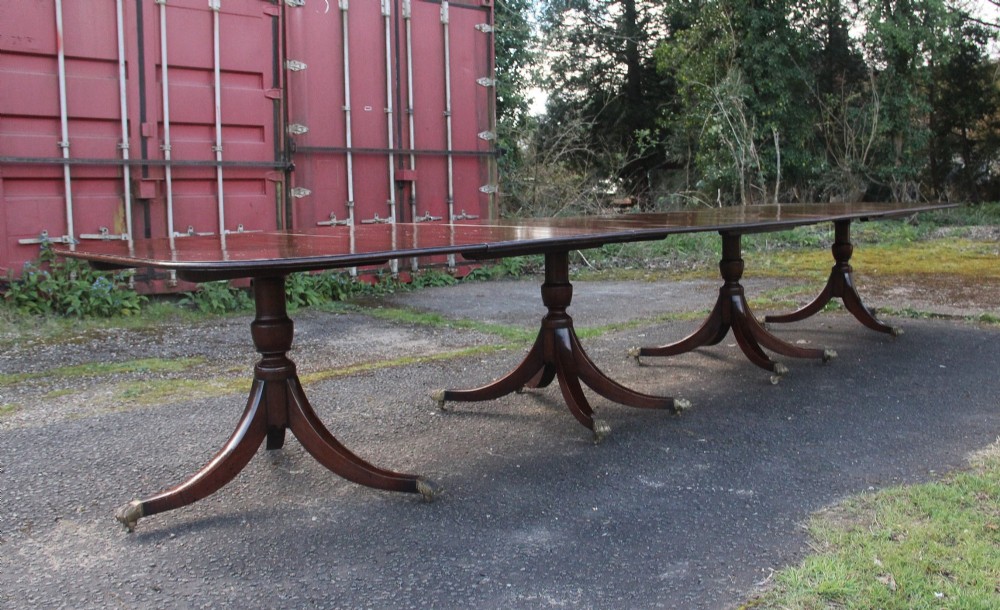 An exceptionally long early twentieth-century mahogany dining table supported by four turned central pedestals with splayed legs ending in brass paw castors. View II
