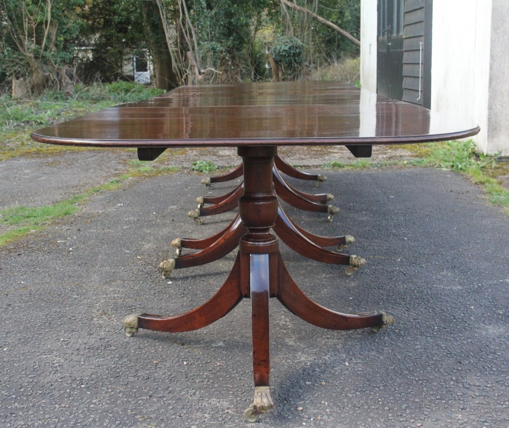 An exceptionally long early twentieth-century mahogany dining table supported by four turned central pedestals with splayed legs ending in brass paw castors. View III
