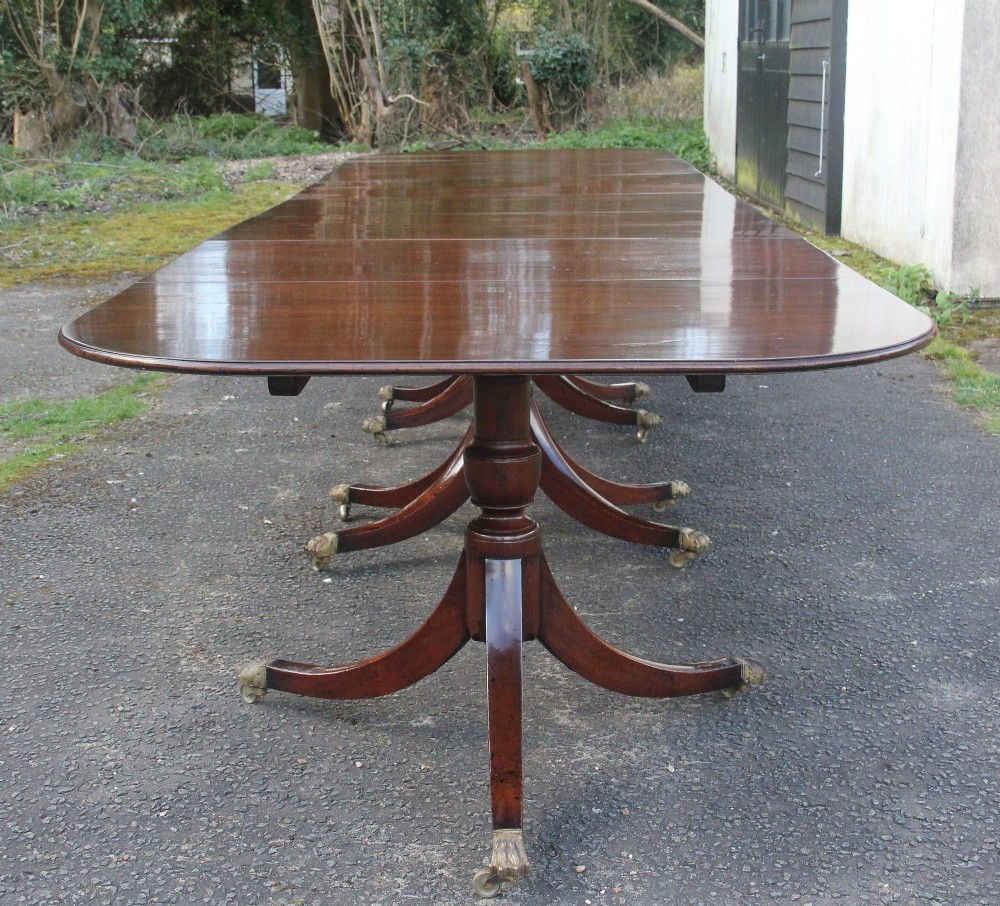 An exceptionally long early twentieth-century mahogany dining table supported by four turned central pedestals with splayed legs ending in brass paw castors. View IV