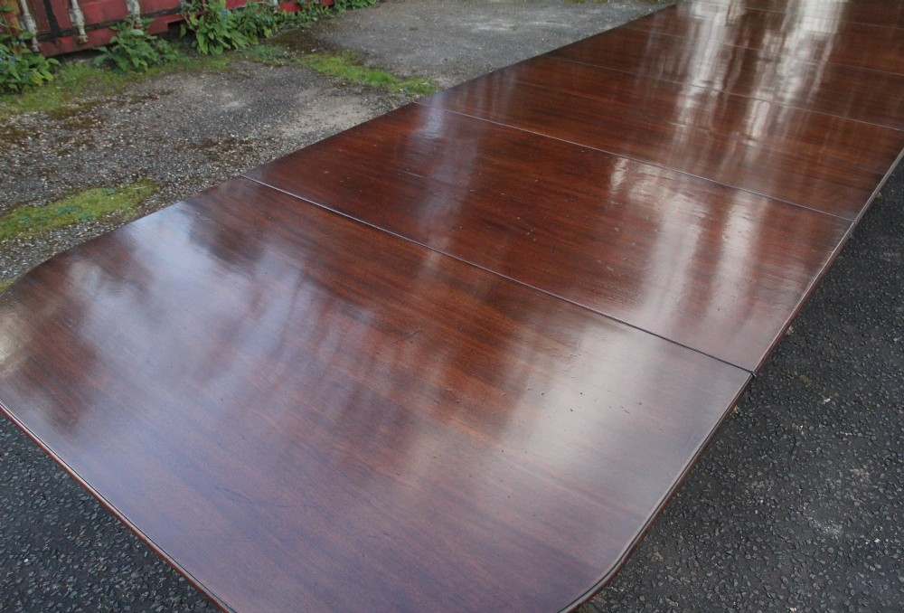 An exceptionally long early twentieth-century mahogany dining table supported by four turned central pedestals with splayed legs ending in brass paw castors. View V