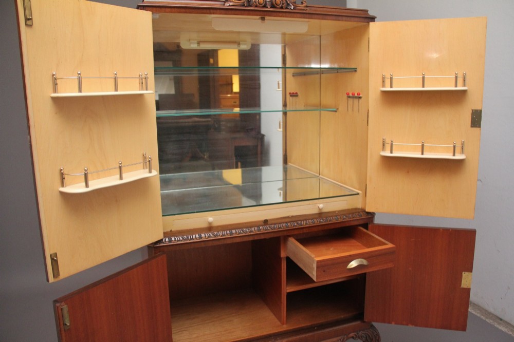 An early 20th-century burr walnut drinks cabinet with decorative pierced brass strap hinges, double doors, and carved cabriole legs. View VI