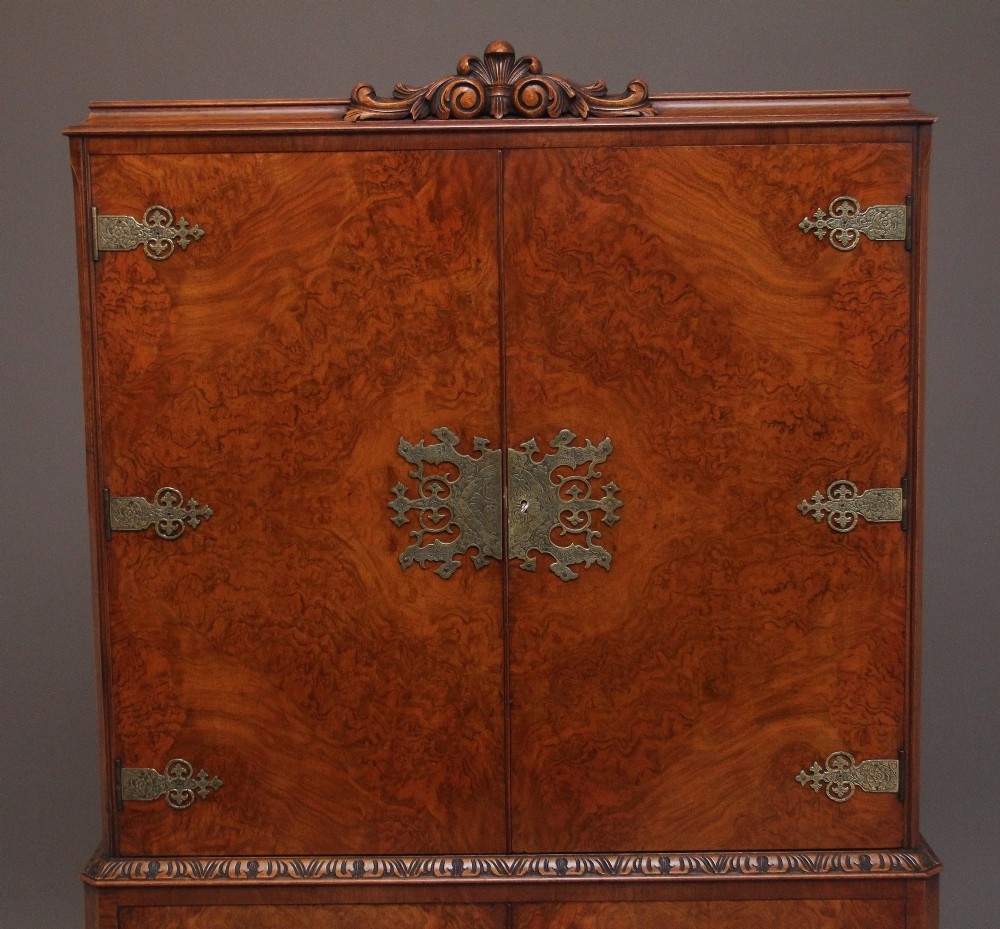 An early 20th-century burr walnut drinks cabinet with decorative pierced brass strap hinges, double doors, and carved cabriole legs. View VII