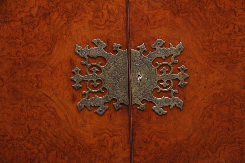 An early 20th-century burr walnut drinks cabinet with decorative pierced brass strap hinges, double doors, and carved cabriole legs. View VIII