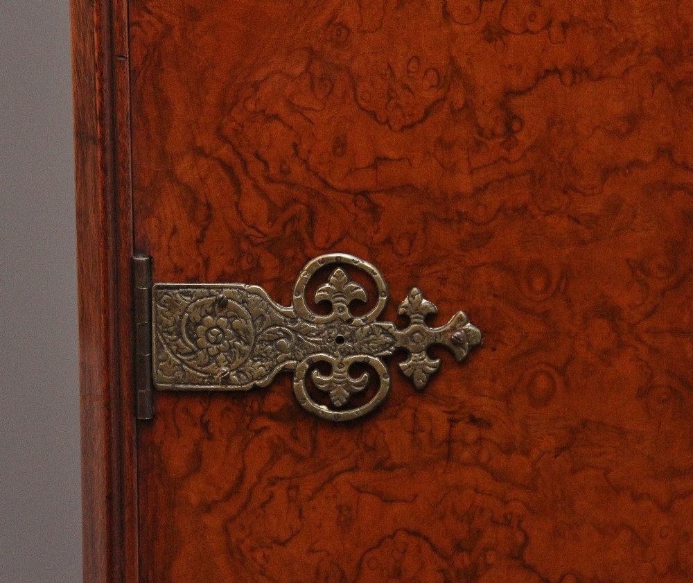 An early 20th-century burr walnut drinks cabinet with decorative pierced brass strap hinges, double doors, and carved cabriole legs. View IX