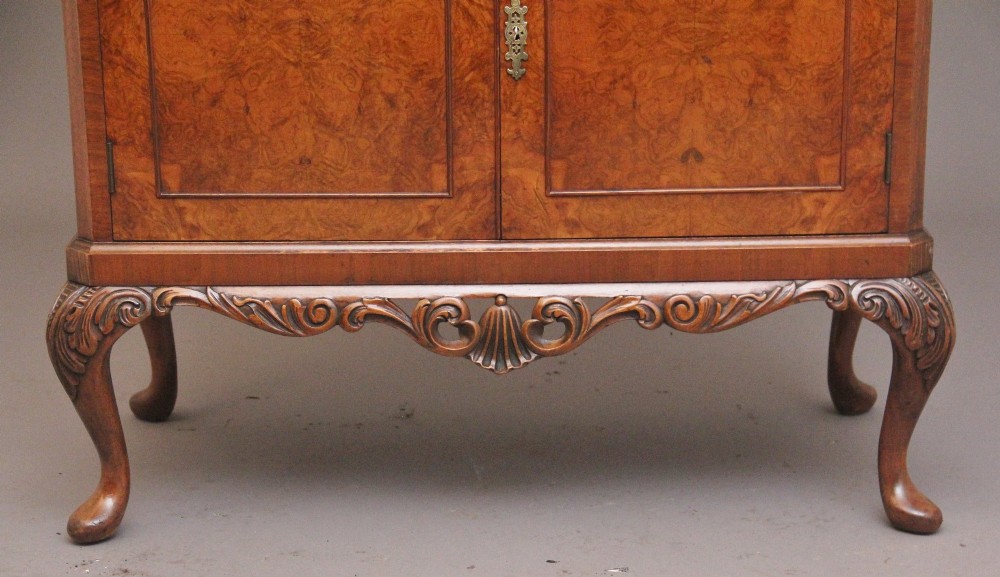 An early 20th-century burr walnut drinks cabinet with decorative pierced brass strap hinges, double doors, and carved cabriole legs. View X