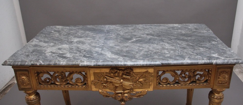 An 18th-century Italian Neoclassical console table featuring a grey marble top, pierced carved giltwood apron with central trophy carving, and fluted tapered legs. View XI