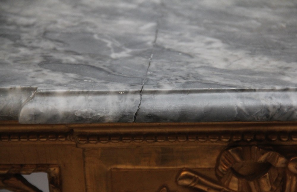 An 18th-century Italian Neoclassical console table featuring a grey marble top, pierced carved giltwood apron with central trophy carving, and fluted tapered legs. View XIII