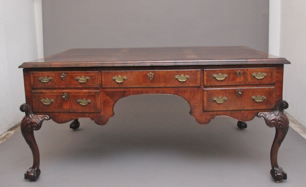 A 19th-century walnut writing desk featuring multiple drawers with brass hardware, a shaped apron, and carved cabriole legs with ball-and-claw feet.