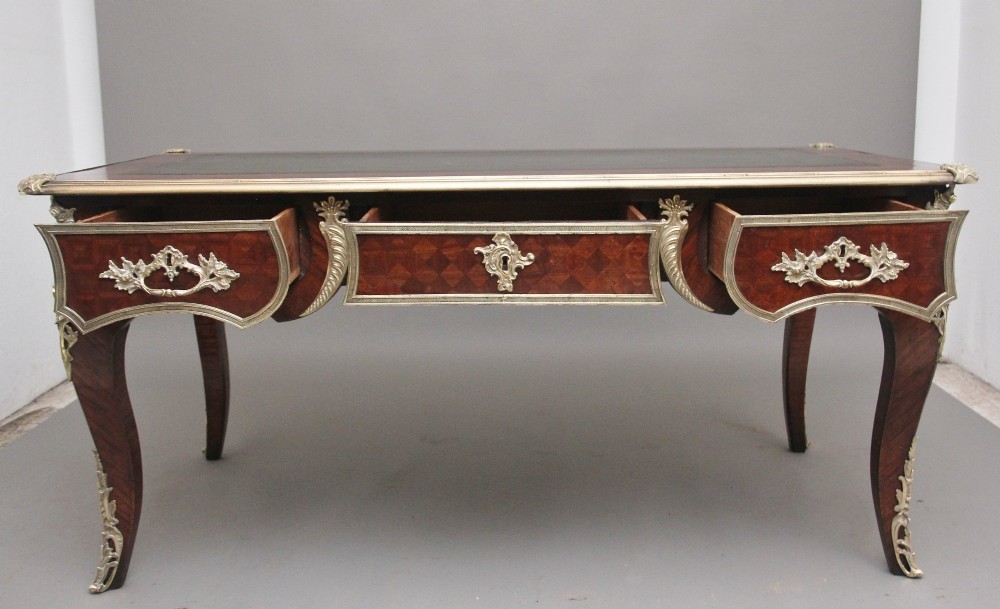 A 19th-century French kingwood writing desk with cabriole legs, ornate gilt-bronze ormolu mounts, three frieze drawers, and a dark inset leather writing top. View II