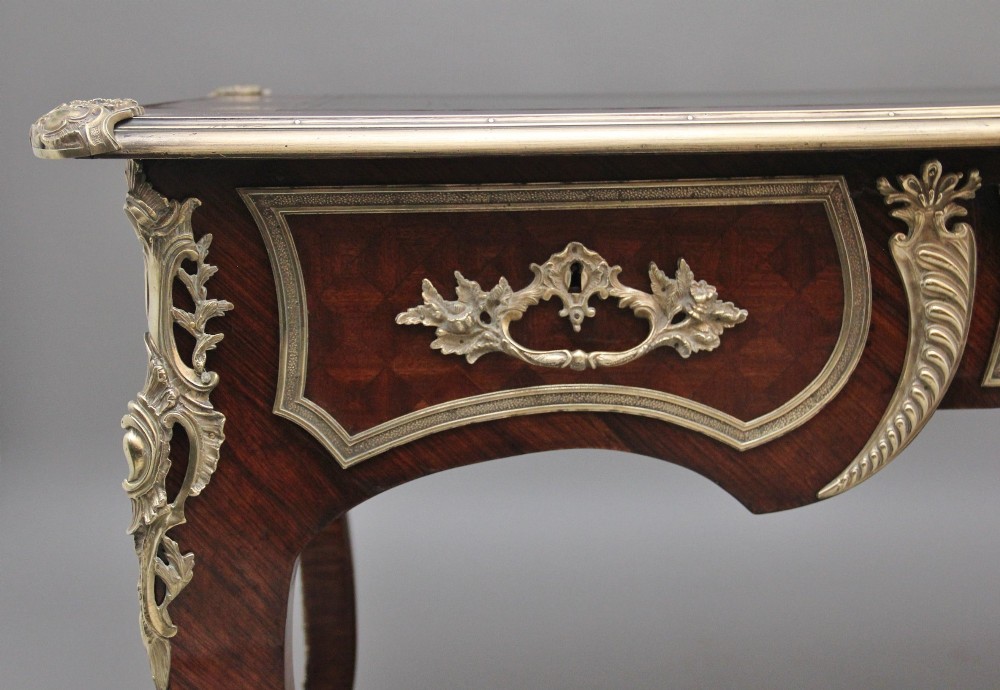 A 19th-century French kingwood writing desk with cabriole legs, ornate gilt-bronze ormolu mounts, three frieze drawers, and a dark inset leather writing top. View III