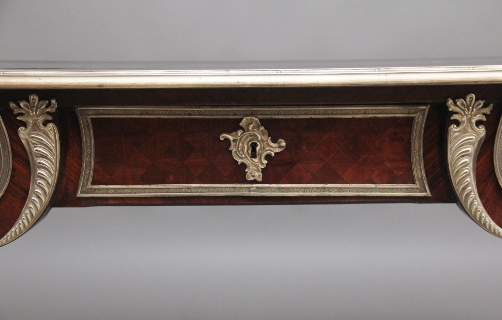 A 19th-century French kingwood writing desk with cabriole legs, ornate gilt-bronze ormolu mounts, three frieze drawers, and a dark inset leather writing top. View IV