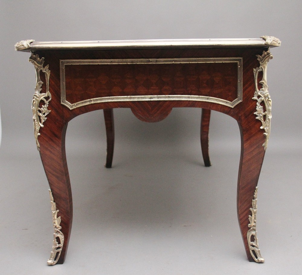 A 19th-century French kingwood writing desk with cabriole legs, ornate gilt-bronze ormolu mounts, three frieze drawers, and a dark inset leather writing top. View VI