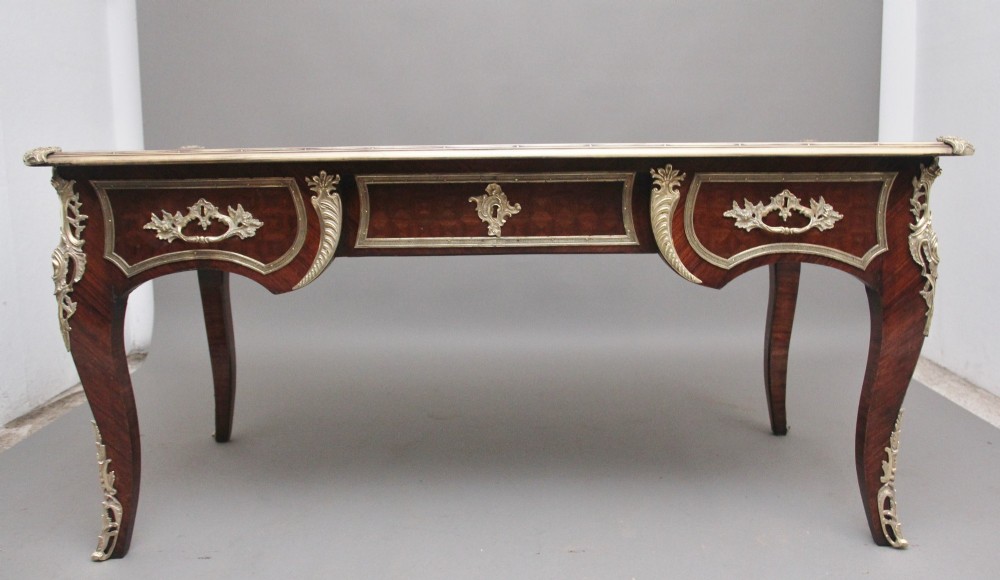 A 19th-century French kingwood writing desk with cabriole legs, ornate gilt-bronze ormolu mounts, three frieze drawers, and a dark inset leather writing top. View VII