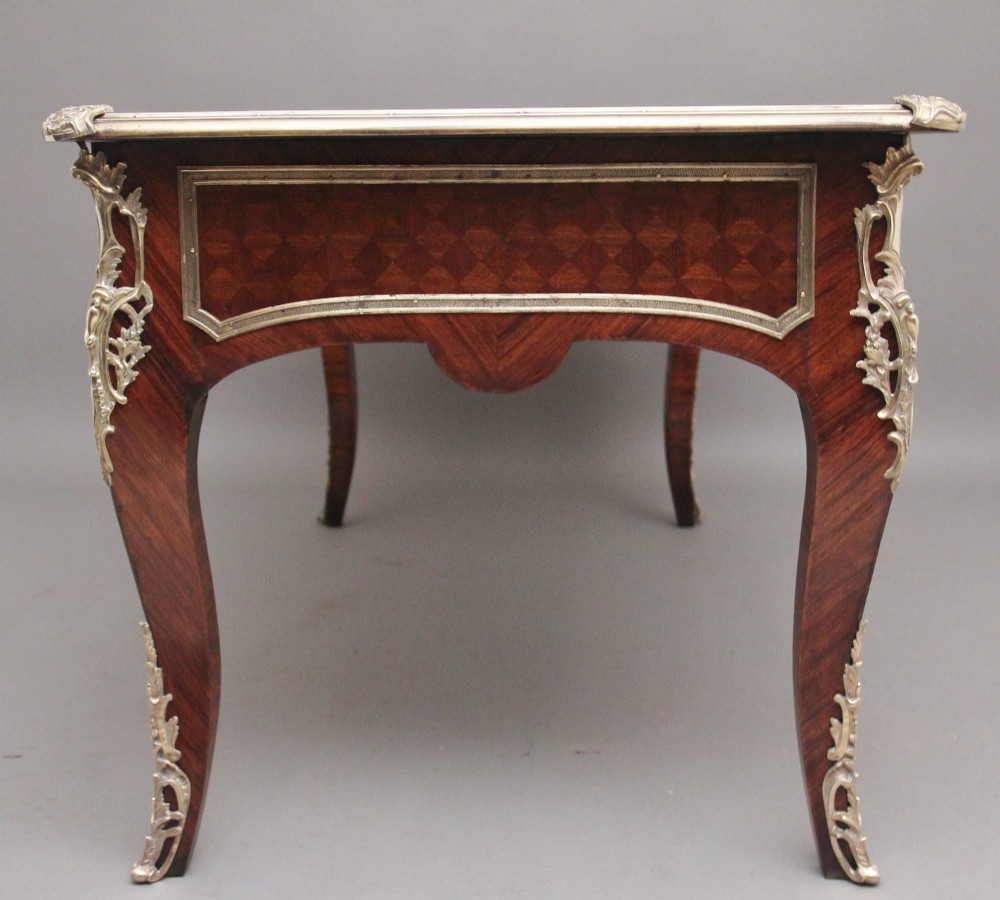 A 19th-century French kingwood writing desk with cabriole legs, ornate gilt-bronze ormolu mounts, three frieze drawers, and a dark inset leather writing top. View VIII