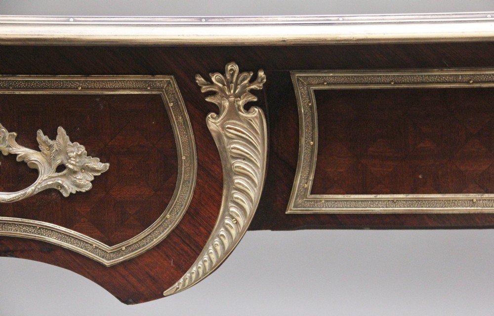 A 19th-century French kingwood writing desk with cabriole legs, ornate gilt-bronze ormolu mounts, three frieze drawers, and a dark inset leather writing top. View XIII
