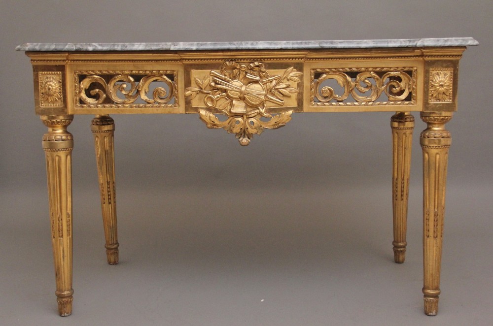 An 18th-century Italian Neoclassical giltwood console table featuring a grey marble top, openwork carved frieze with a central trophy motif, and fluted tapered legs. View XIII