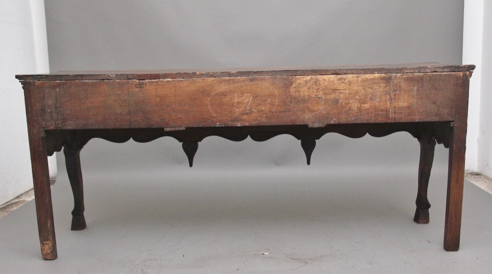An early 18th-century oak dresser base featuring three brass-handled drawers, a scalloped apron with pendant drops, and cabriole legs. View VIII