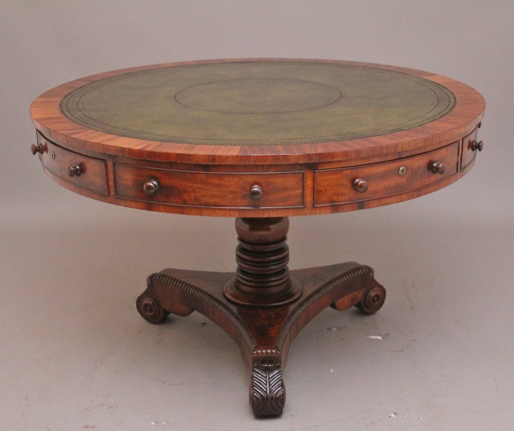 An early 19th century circular mahogany drum table featuring an inset green leather top, frieze drawers with knob handles, and a turned pedestal base.