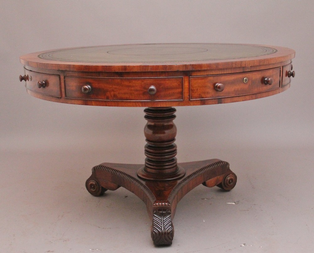 An early 19th century circular mahogany drum table featuring an inset green leather top, frieze drawers with knob handles, and a turned pedestal base. View IX