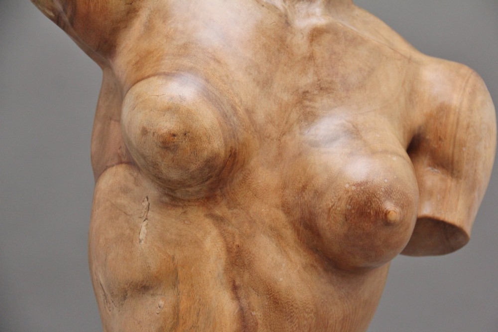A life-size early twentieth-century sculpture of a female torso carved from natural timber with visible wood grain and a smooth finish. View XI