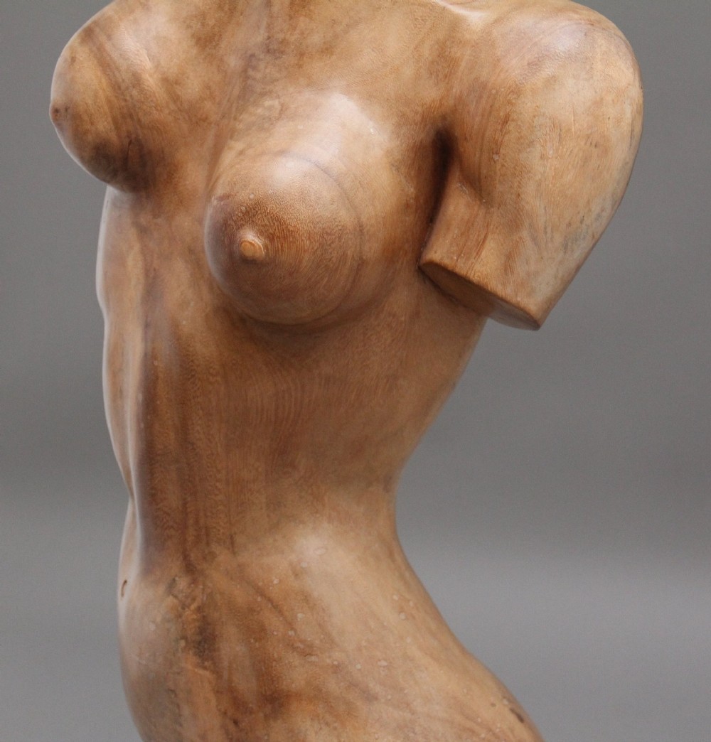A life-size early twentieth-century sculpture of a female torso carved from natural timber with visible wood grain and a smooth finish. View XII