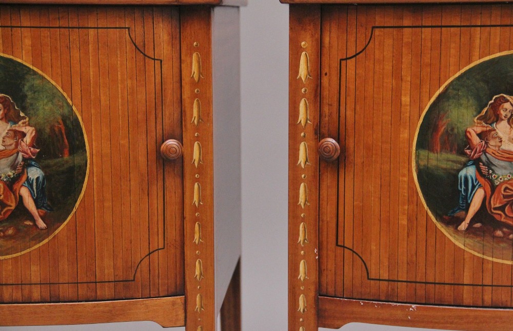 A pair of tall early 20th-century satinwood bedside cabinets featuring hand-painted classical figural medallions and tapered square legs. View V