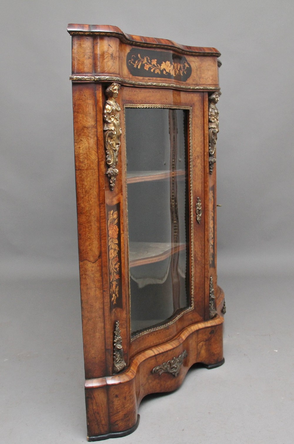 A Victorian burr walnut credenza featuring central floral marquetry, curved side glass doors, and gilt metal mounts. View VI