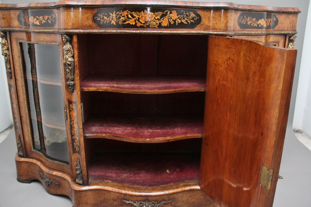 A Victorian burr walnut credenza featuring central floral marquetry, curved side glass doors, and gilt metal mounts. View IX