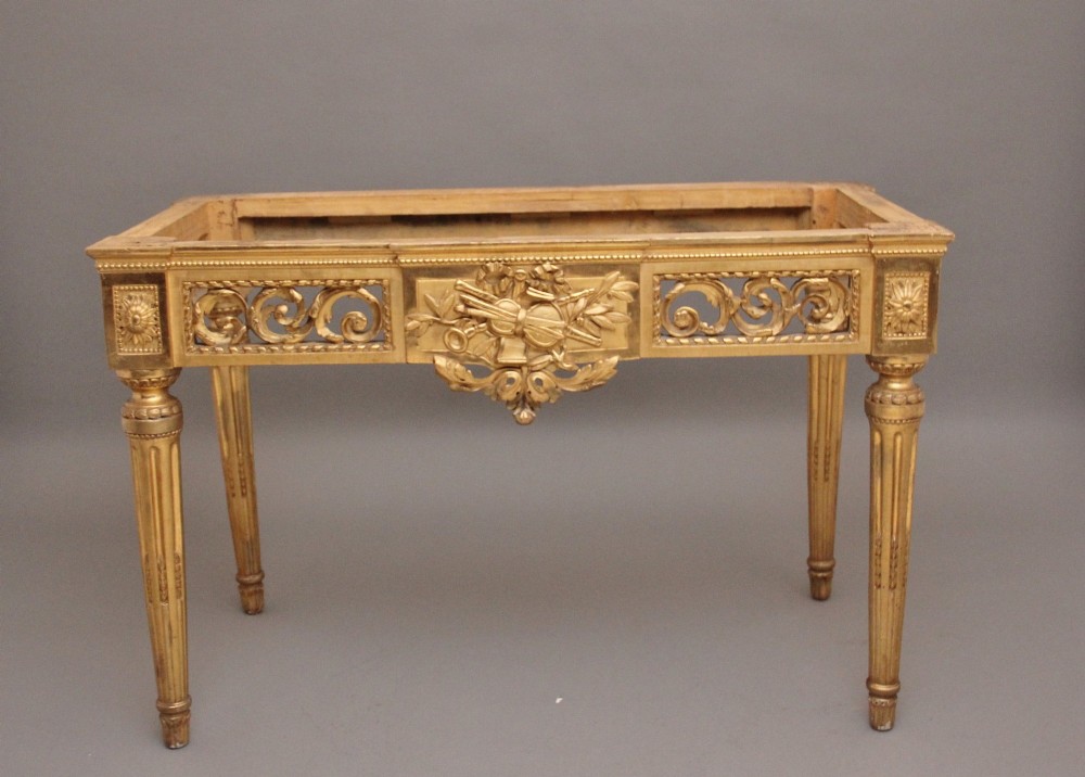 An 18th-century Italian giltwood console table featuring fluted tapered legs, an ornate carved central motif, and a grey marble top. View XI