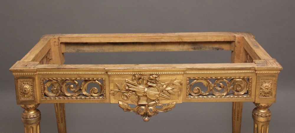 An 18th-century Italian giltwood console table featuring fluted tapered legs, an ornate carved central motif, and a grey marble top. View XIII