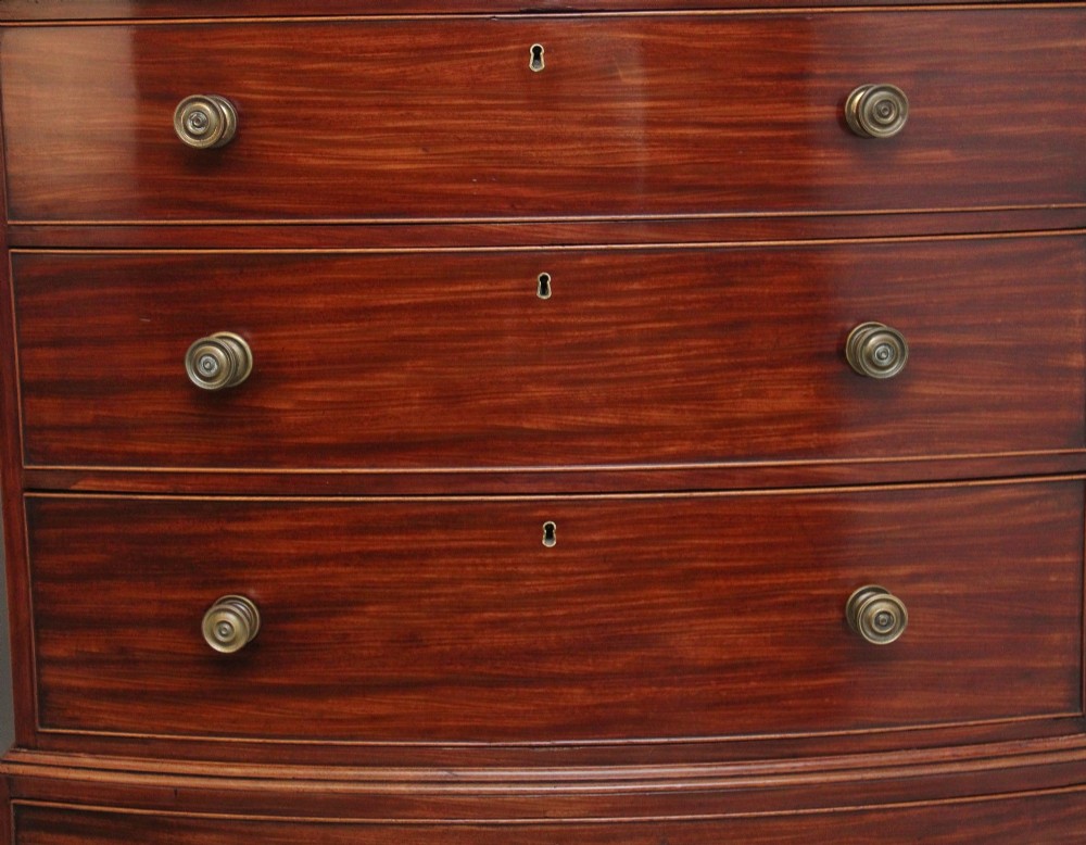 An early nineteenth-century mahogany bow-front tallboy featuring seven stacked drawers with turned brass handles. View V