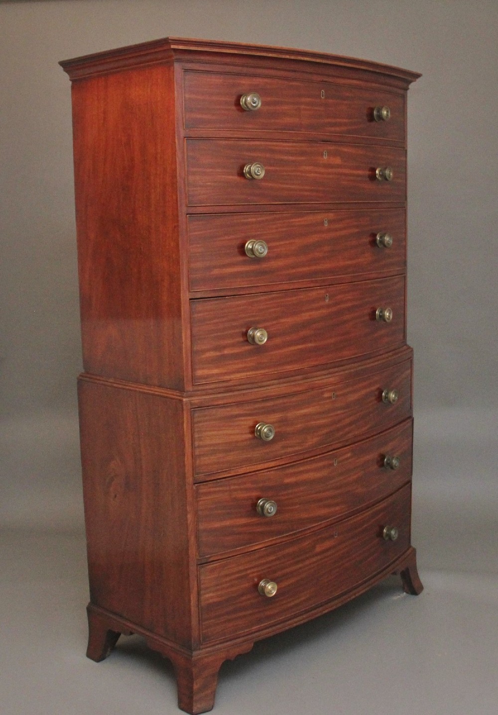 An early nineteenth-century mahogany bow-front tallboy featuring seven stacked drawers with turned brass handles. View VIII