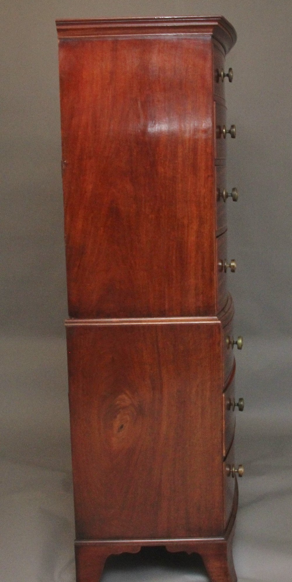 An early nineteenth-century mahogany bow-front tallboy featuring seven stacked drawers with turned brass handles. View X