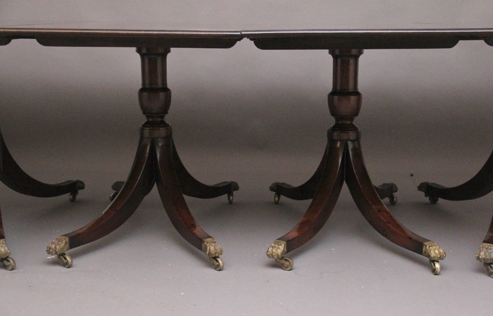 A large early 20th-century mahogany four-pedestal dining table with splayed legs and brass castors. View X