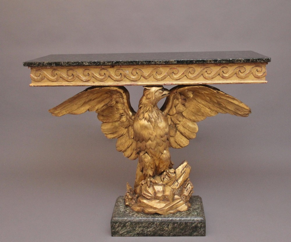 An early 20th-century Neoclassical style console table featuring a sculpted gold eagle base supporting a dark green marble tabletop.