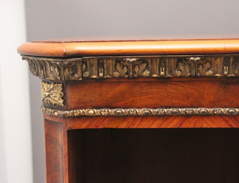 A nineteenth-century low breakfront open bookcase crafted from burr walnut with gilt-bronze ormolu mounts along the top border and base. View VII