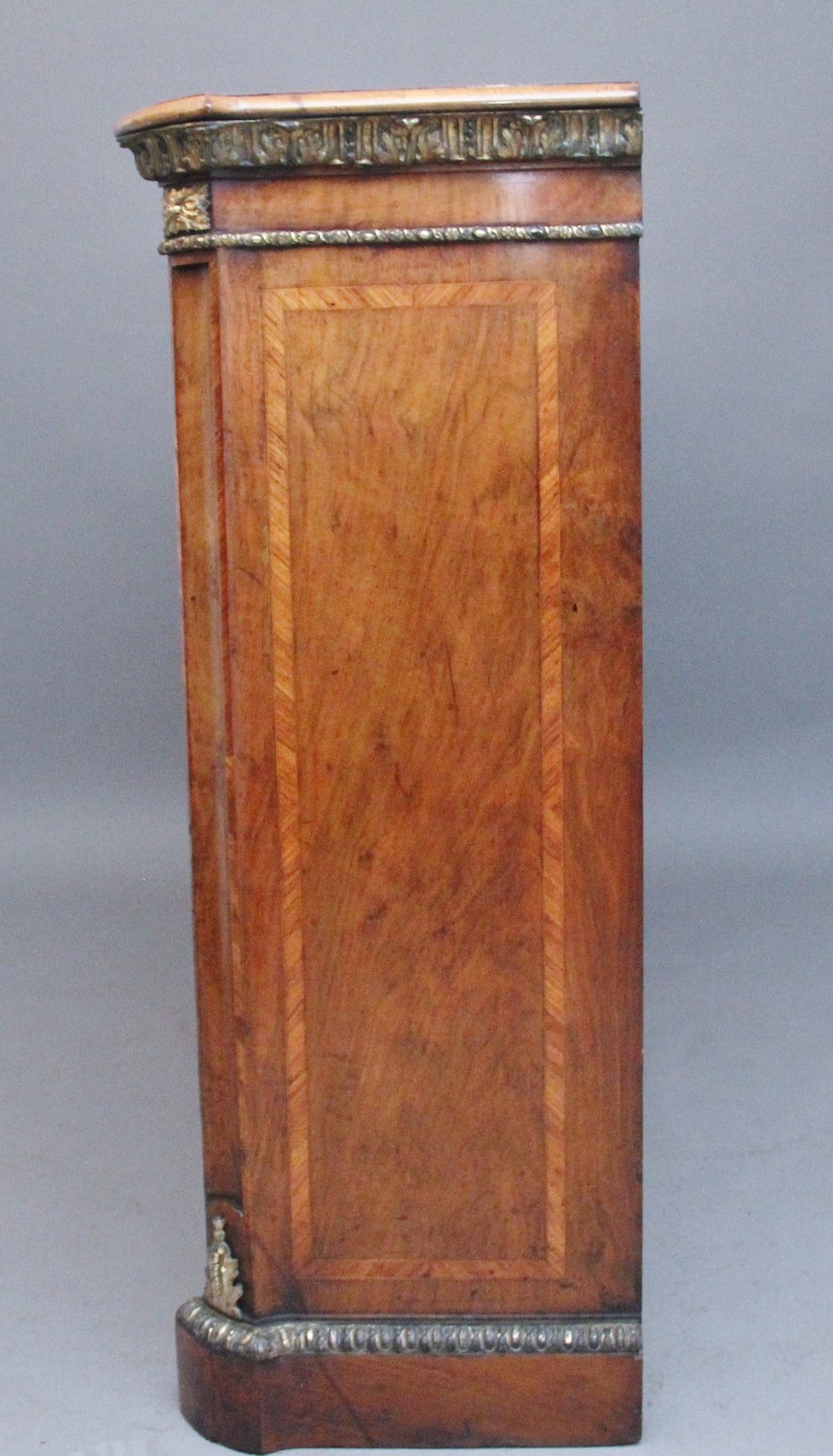 A nineteenth-century low breakfront open bookcase crafted from burr walnut with gilt-bronze ormolu mounts along the top border and base. View XIII