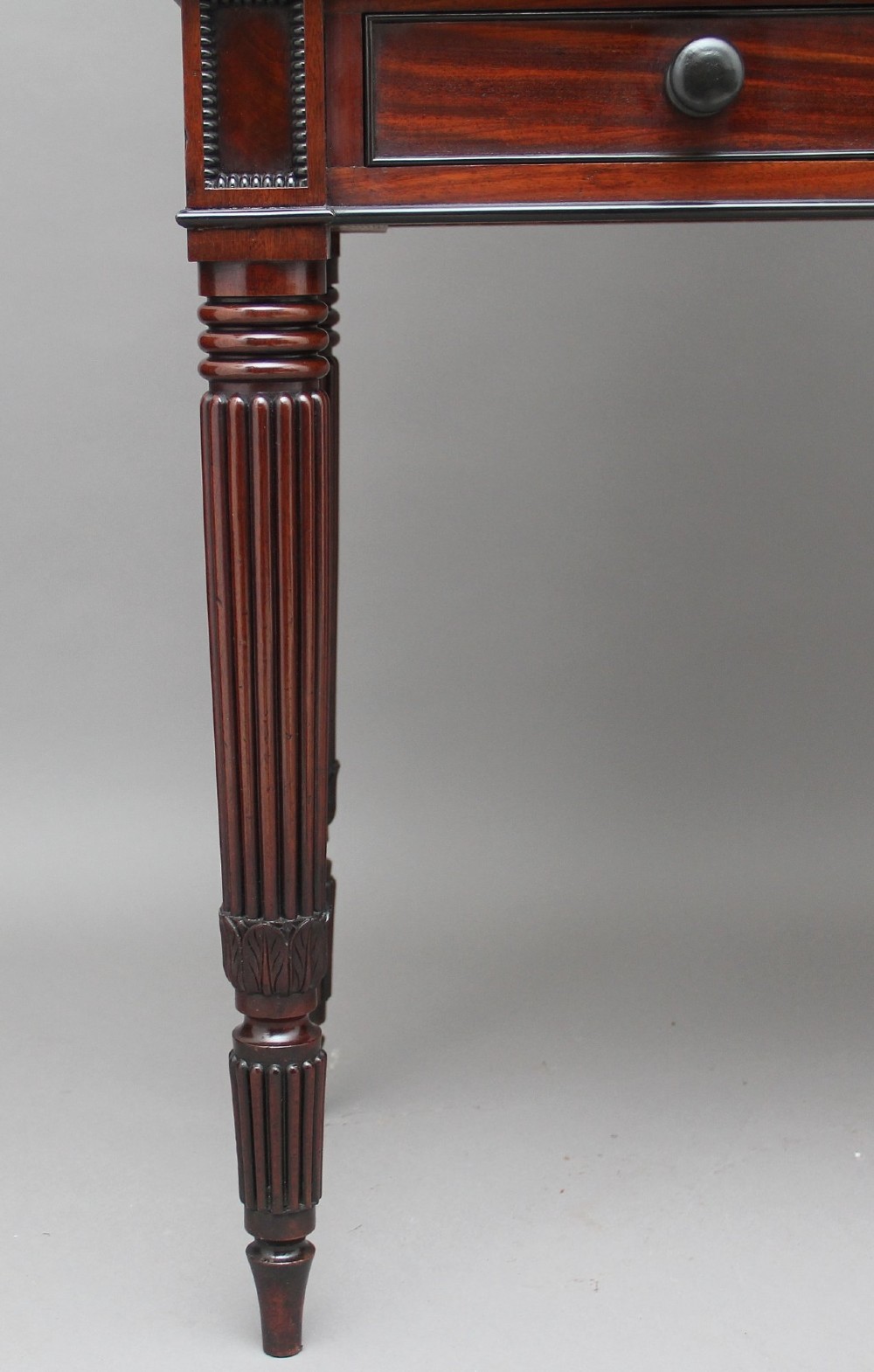 An early 19th-century mahogany collectors cabinet on stand featuring flame mahogany door panels, a single drawer, and four turned reeded legs. View IX