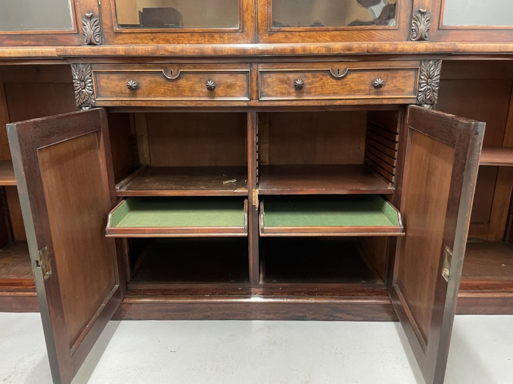 An early nineteenth-century mahogany breakfront bookcase featuring four glazed upper doors over four panelled lower cupboard doors. View V