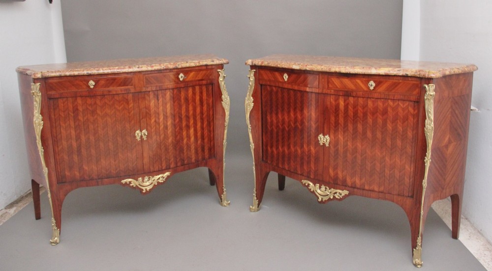 A pair of 19th-century French kingwood commodes featuring chevron parquetry veneer, mottled brown marble tops, and decorative gilt-bronze mounts. View II