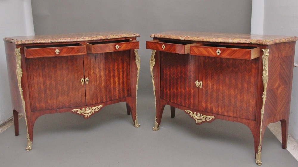 A pair of 19th-century French kingwood commodes featuring chevron parquetry veneer, mottled brown marble tops, and decorative gilt-bronze mounts. View III